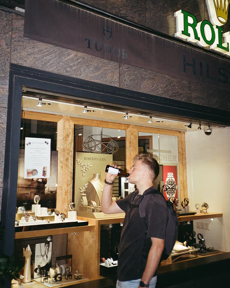 Freelance designer and Webflow developer Jaroslav Dlask drinking beer in front of a Rolex store.